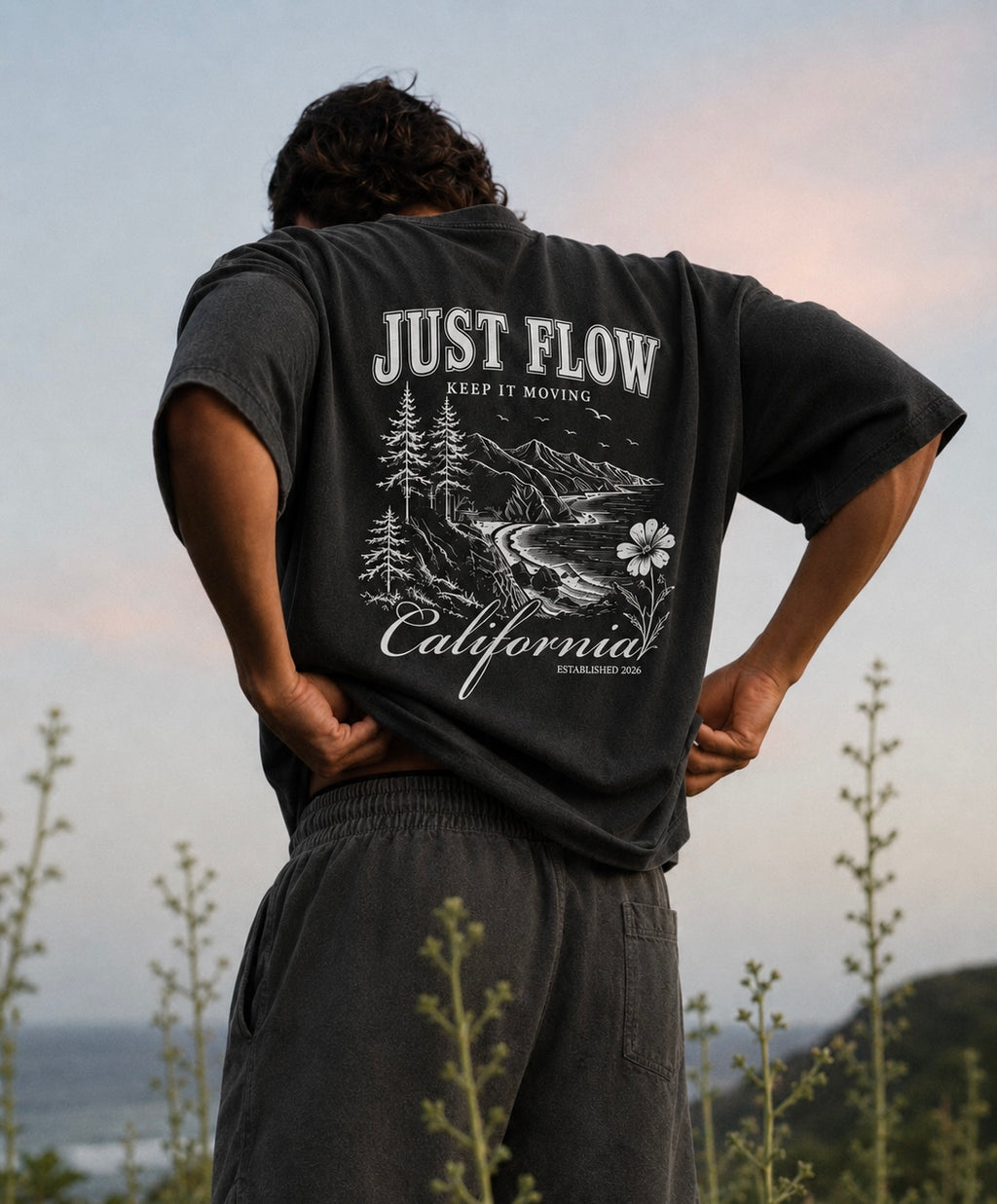 California Hibiscus Heavyweight Tee in washed black, back print, coastal bluff at sunset