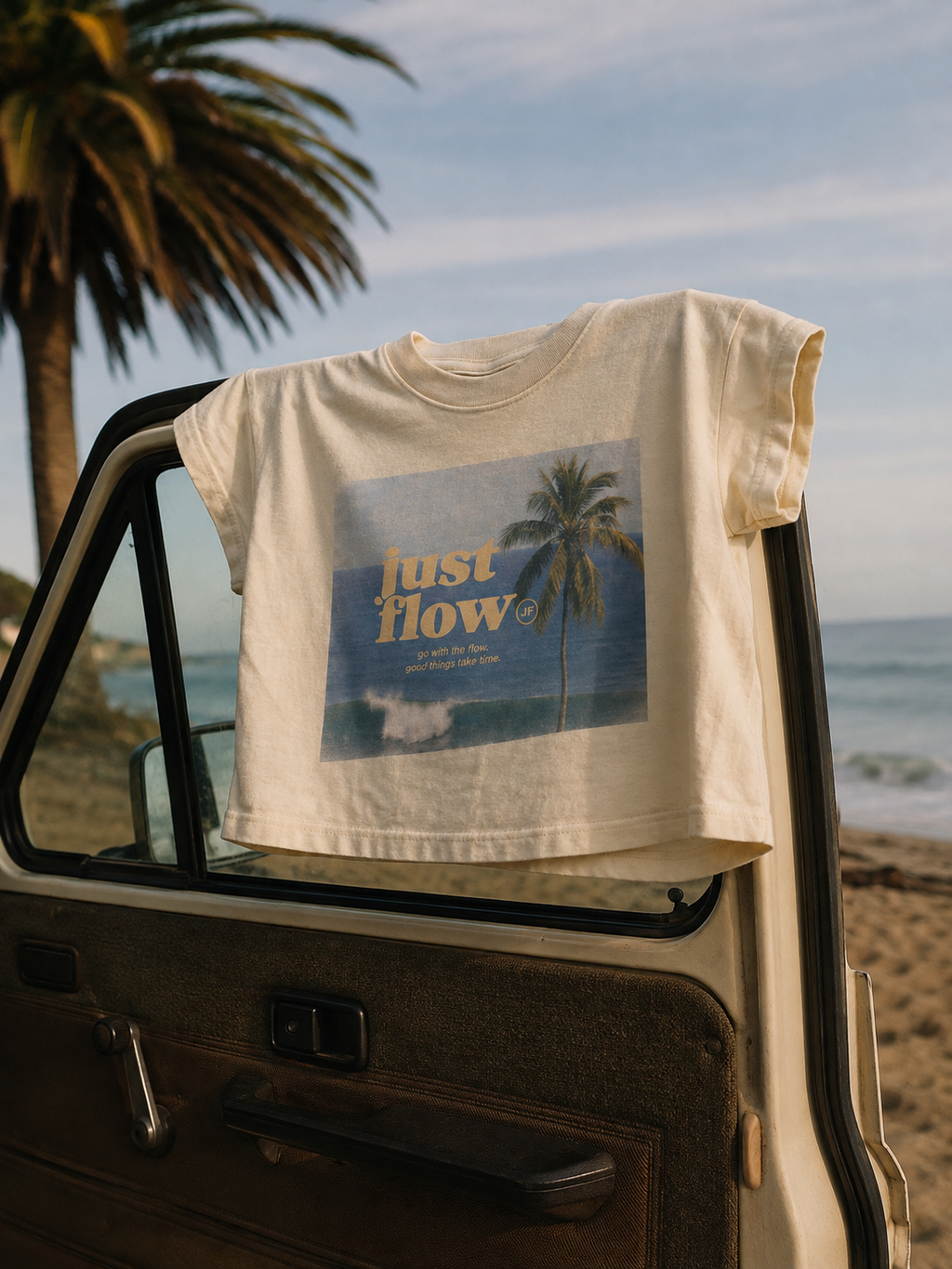 Postcard Cropped Tee in vintage white, on a truck door at the beach
