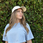 Minimal Wordmark Cropped Tee in periwinkle, worn with a Just Flow cap against a hedge in San Diego