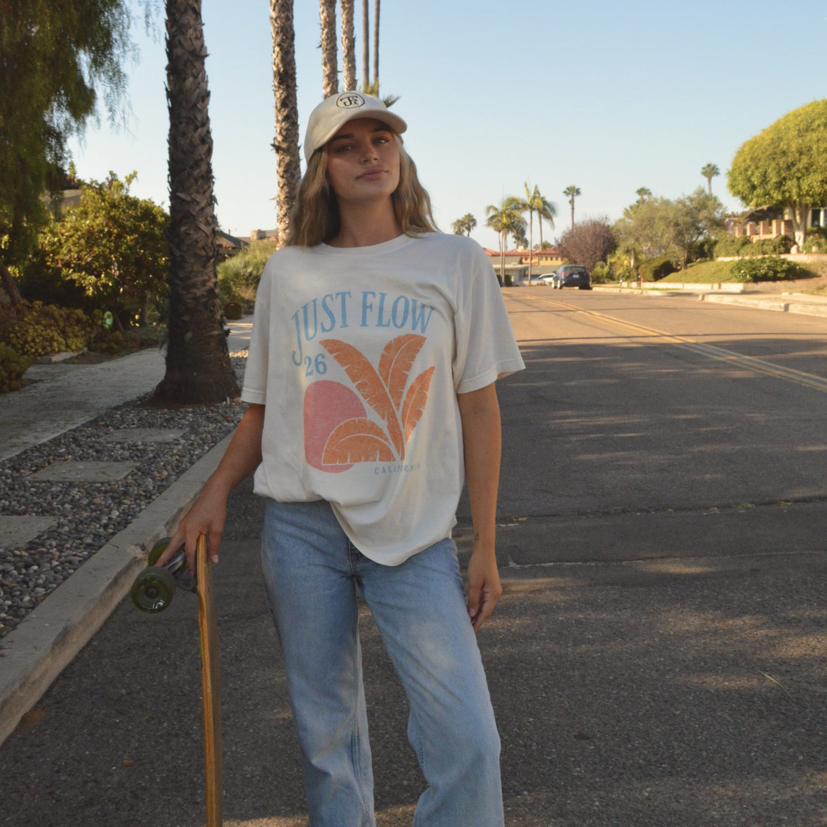 Retro Graphic Oversized Tee in cream, worn on a palm lined San Diego street at golden hour