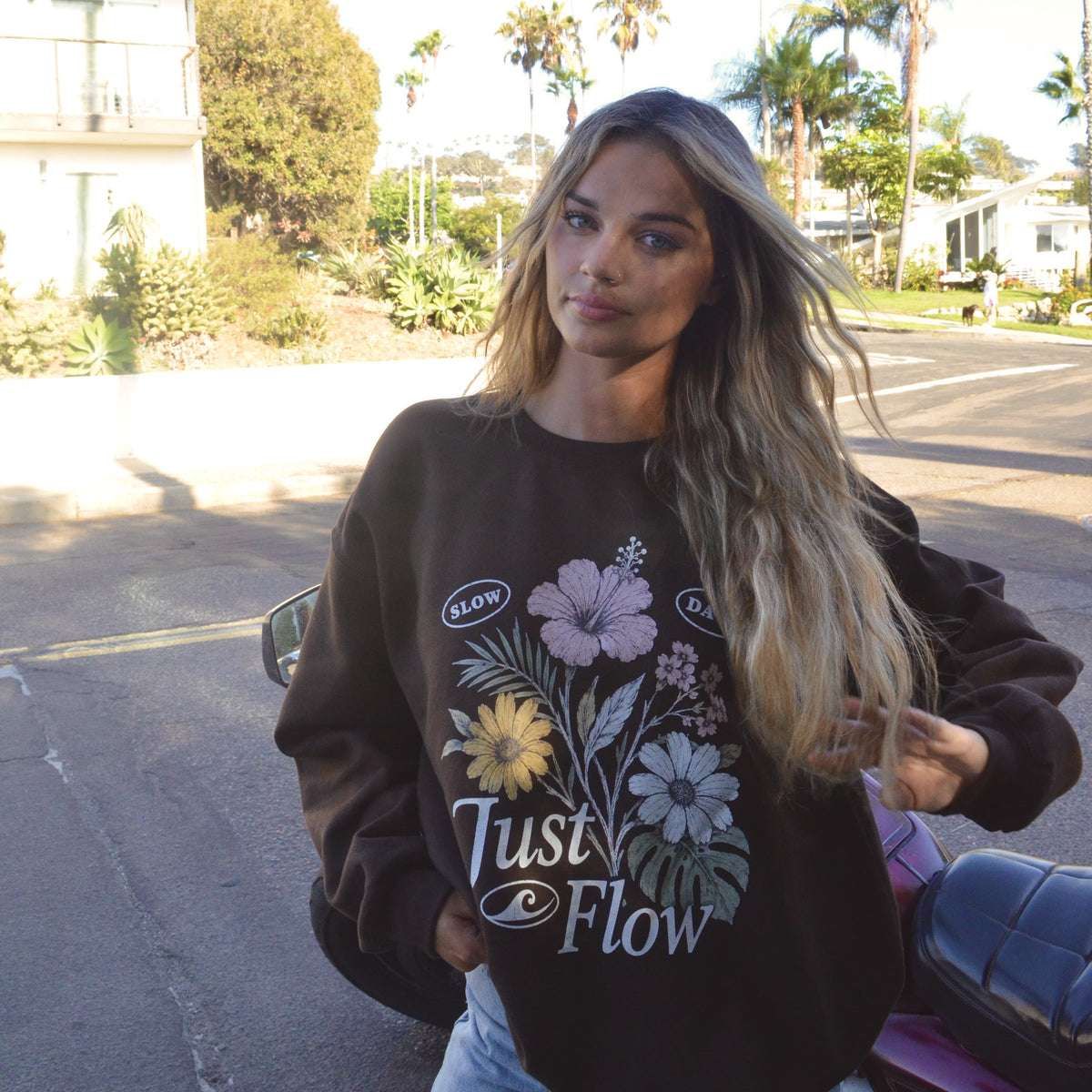 Slow Days Graphic Crew Sweatshirt in brown, worn on a palm lined San Diego street at golden hour