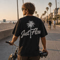 Black palm script heavyweight tee on the boardwalk with a beach cruiser