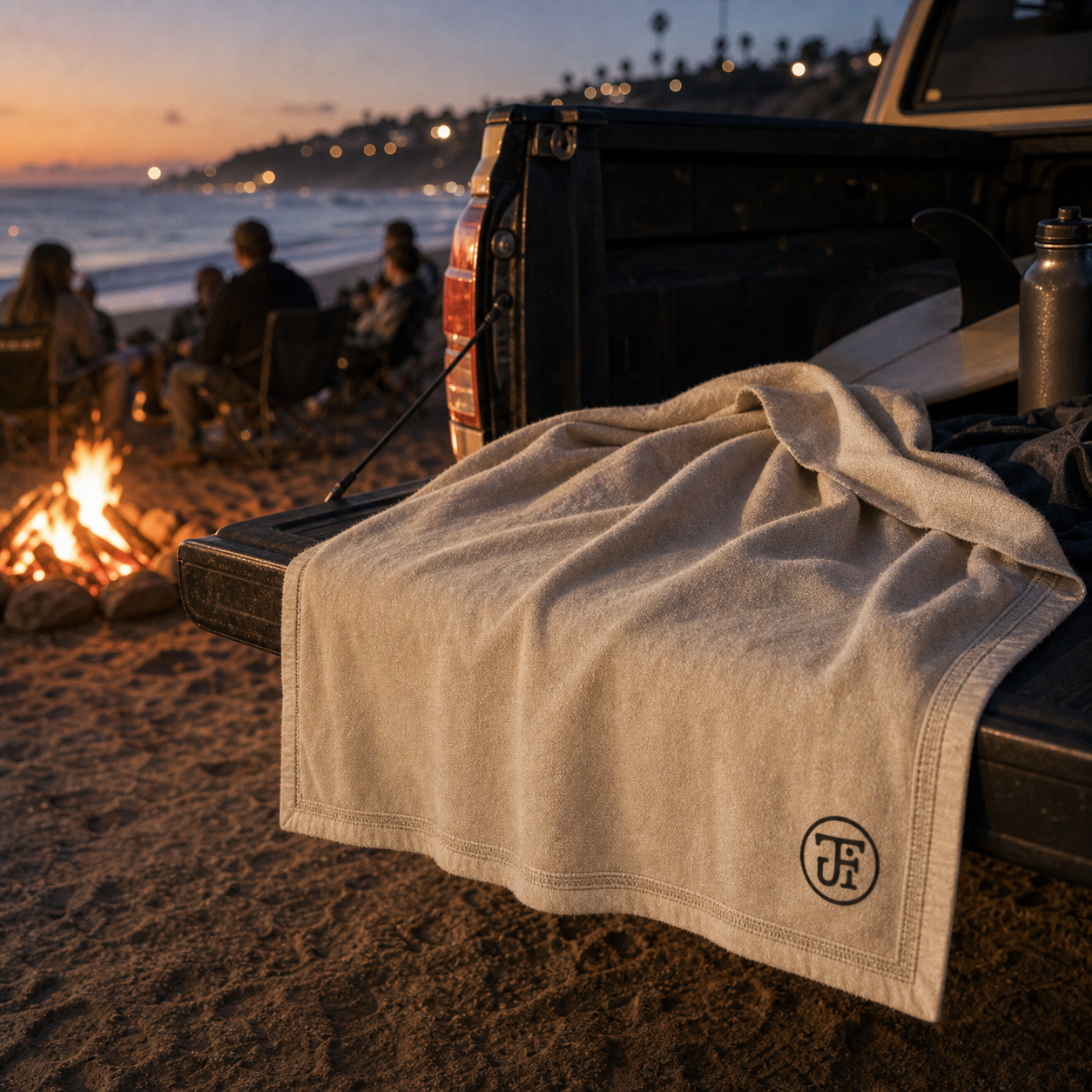 Monogram stadium blanket over a truck tailgate at a beach bonfire